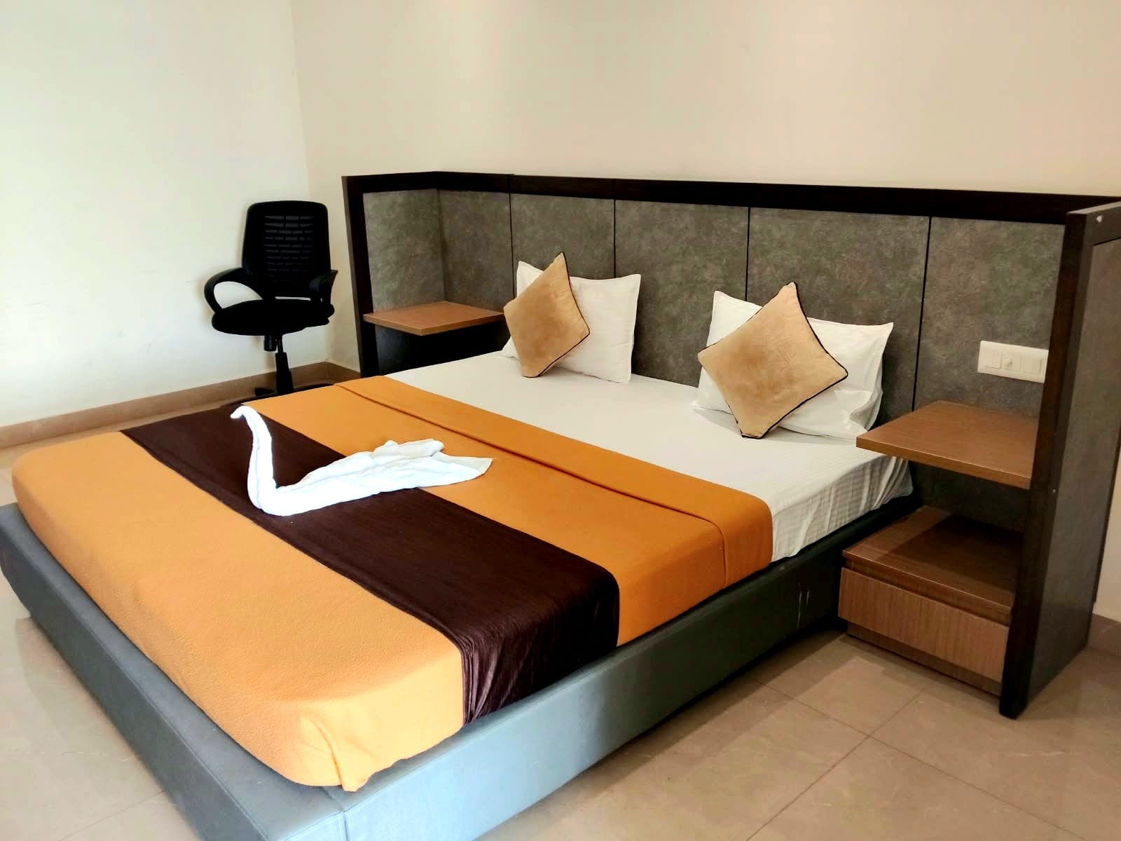 Double bed with fresh white linen, cushions and bedside shelves in a deluxe room
