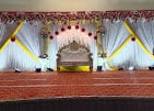 Stage with white drapes and yellow-and-red garlands at a past function