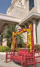 Red wooden swing decorated with marigold garlands outside the building